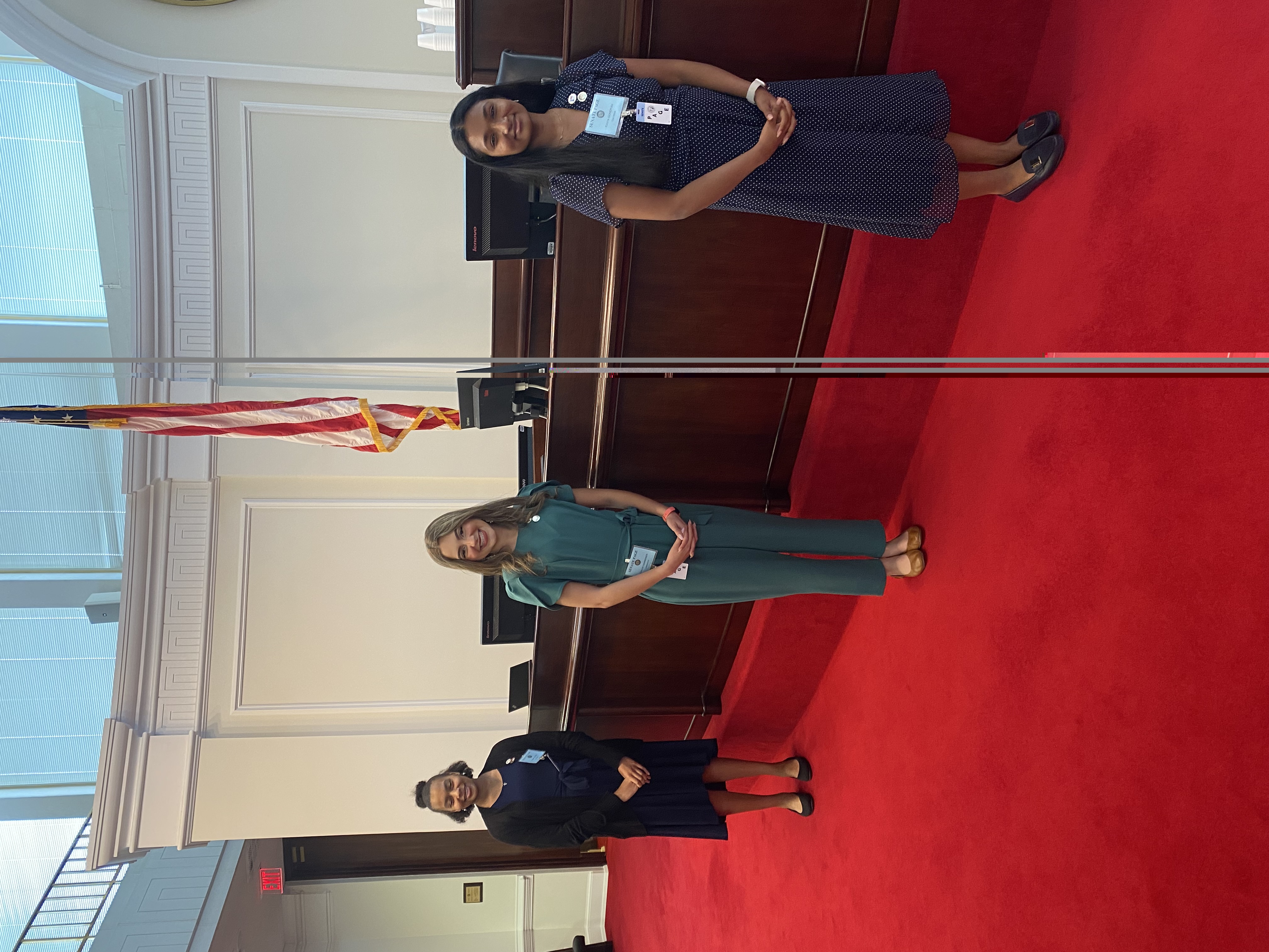 Three Senate Pages standing in front of Senate chamber dais.